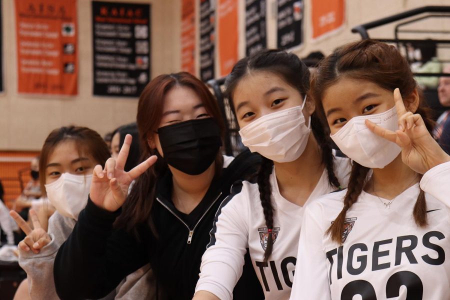(From left to right) Sarah Yim (12), Yenna Ko (12), Aimee Choi (12), and Julia Cheon (12) pose for the camera while watching the varsity boys game.