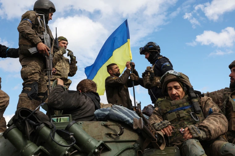 Ukrainian soldiers adjust the Ukrainian flag. (Source: NBC News)