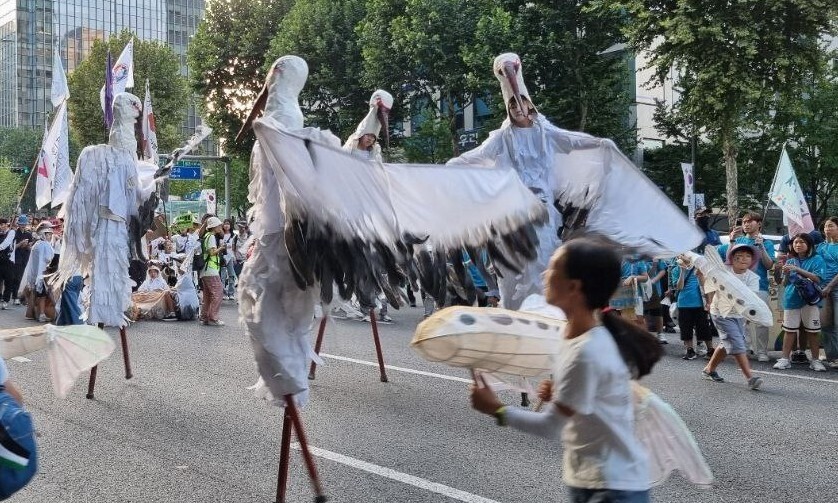 Protestors in stork costumes walking down central Gangnam