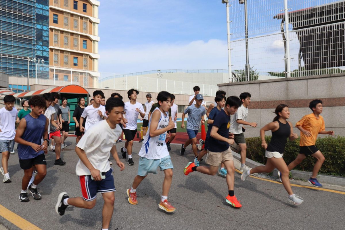 Members of the cross country team maintain their pace as they run down a hill
