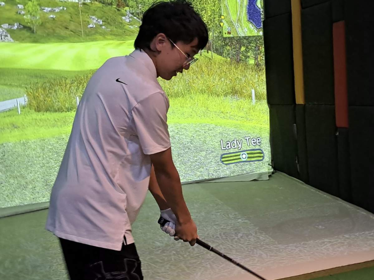Joonho Kim (12) tees off in a screen golf match.