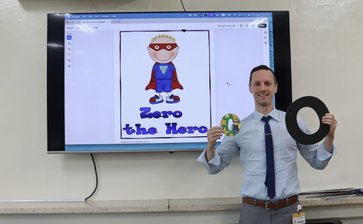 Mr. Desmond holds two zeroes besides a photo of Zero the Hero
