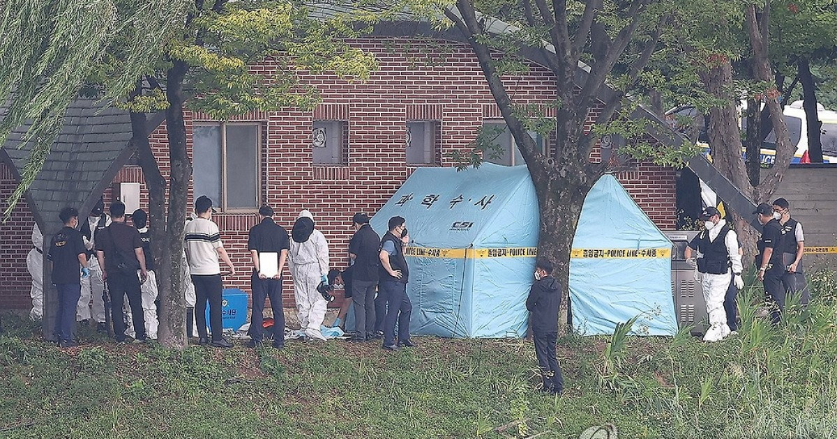 Police officers investigate the scene of the suicide