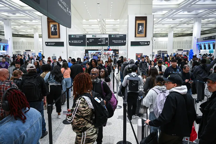 Travelers wait at security checkpoint as line extends to the outside of the airport 